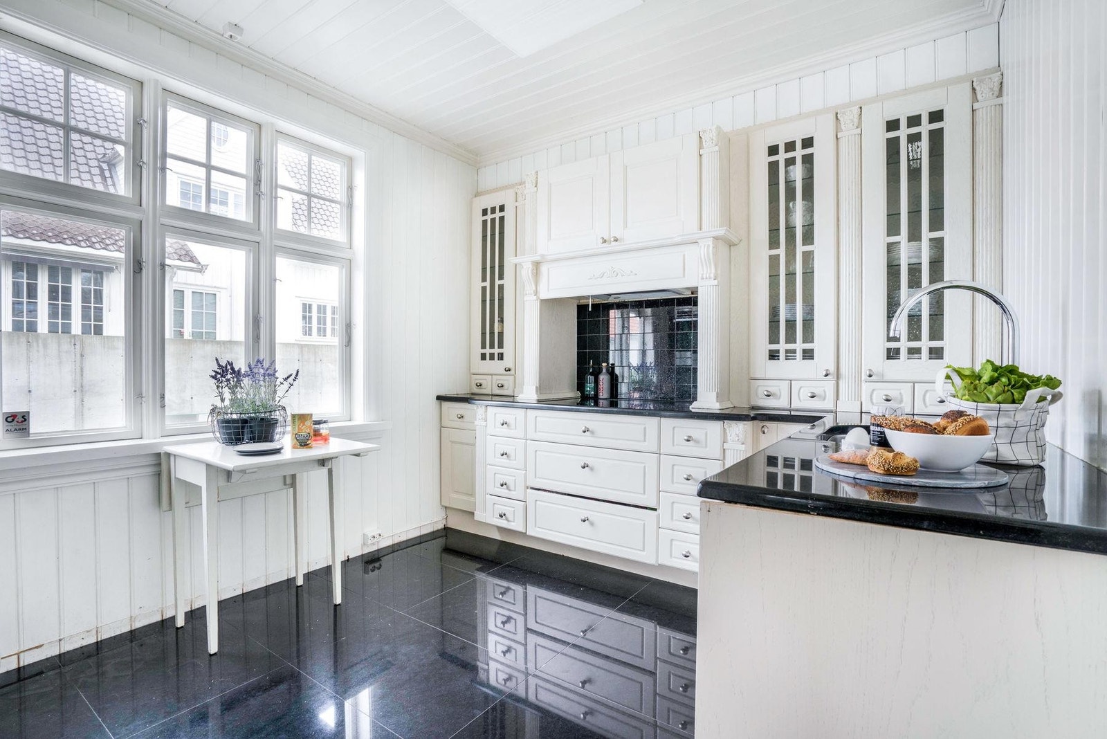 Praktisk flislagt kjøkken med god skapplass.
Lysmalte flater og en solid benkeplate i svart granitt. Integrerte hvitevarer fra Miele. Galleribilde