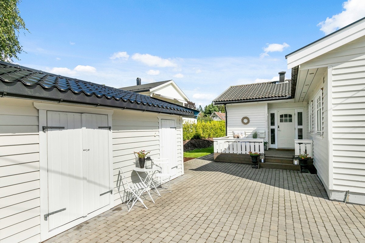 Gårdsplass med belegningsstein og adkomst til en utebod. Galleribilde