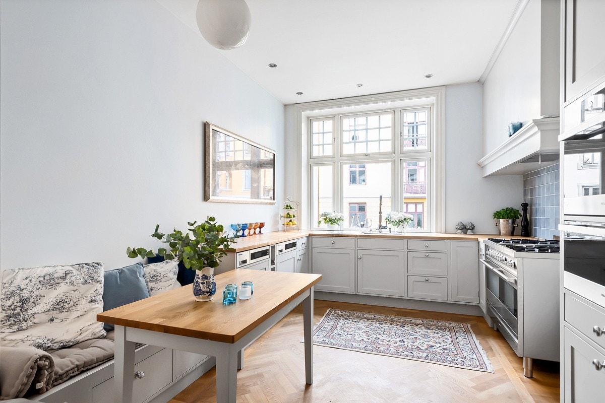 Stort spisekjøkken med snekkerlaget kjøkkeninnredning med profilerte fronter og benkeplater i behandlet tre Galleribilde