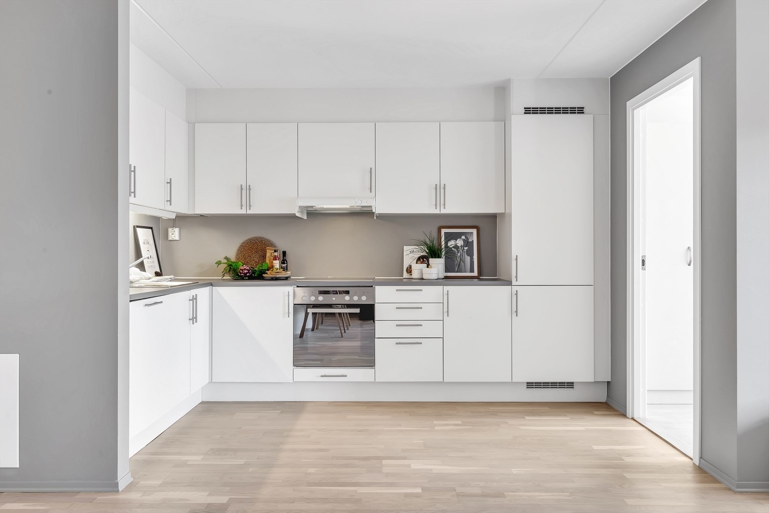 Kjøkken med god benkeplass. God plass til å sette opp en frittstående kjøkkenøy. Kjøkkenet har fronter i malt glatt utførelse. Galleribilde