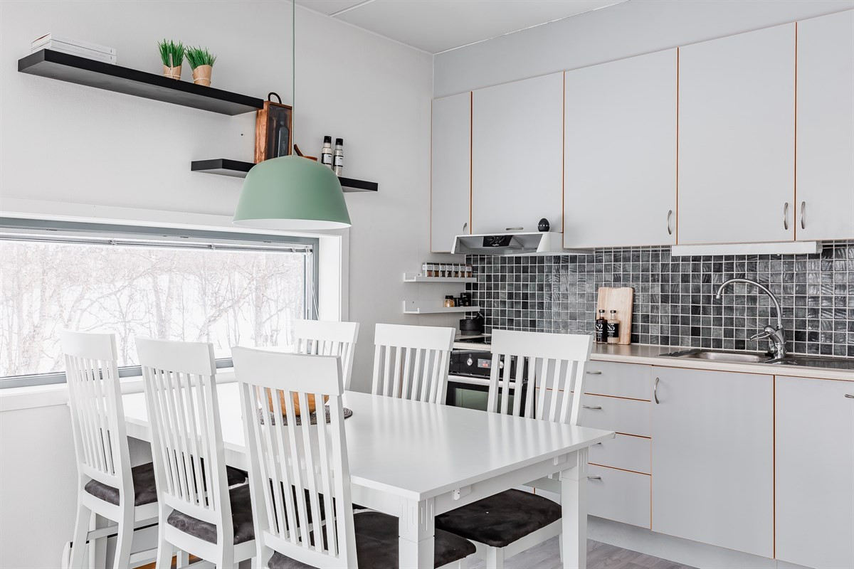 Kjøkken med tidløs innredning, fliser over benk og rom for spiseplass