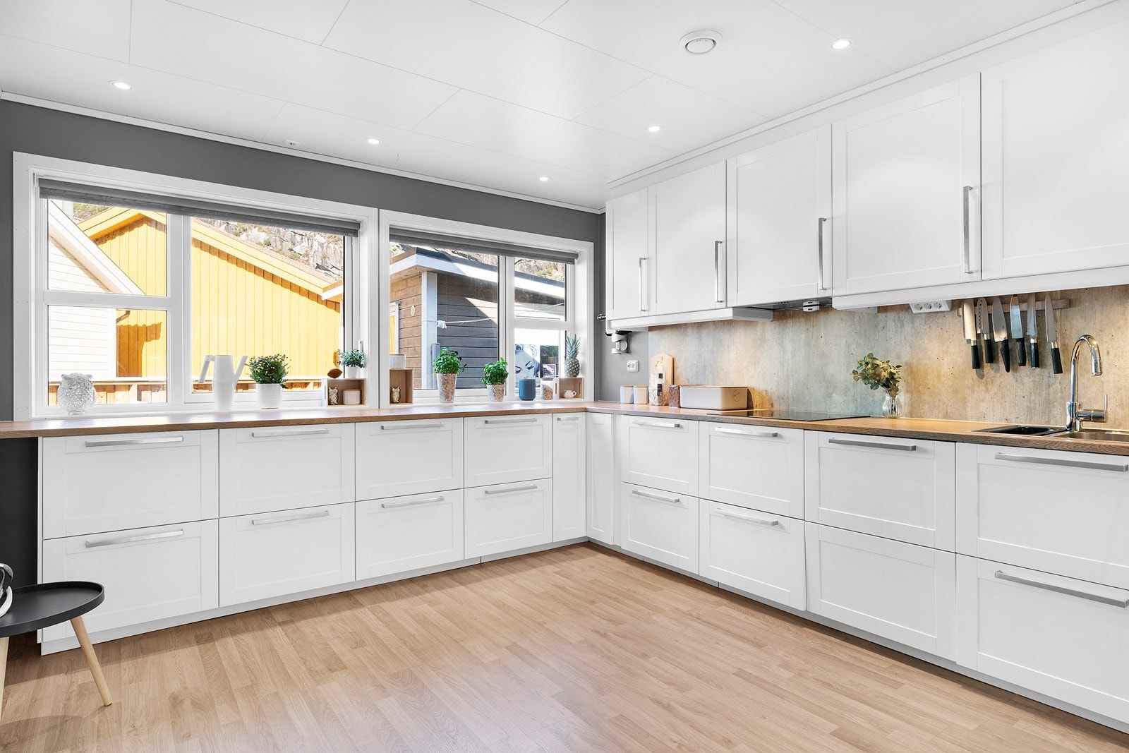 Innbydende hvitt kjøkken med lyse store vindusflater som gir godt med lys Galleribilde