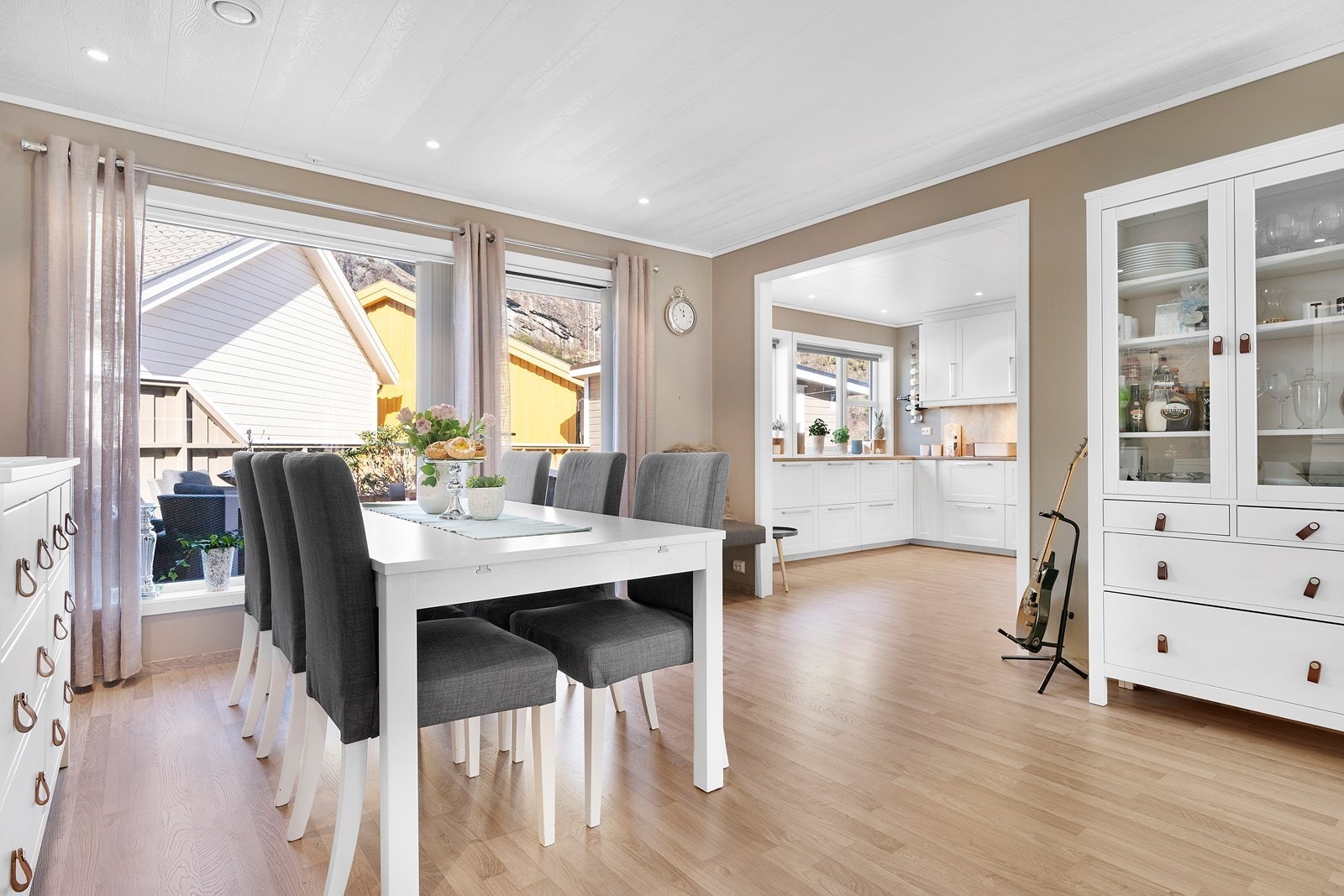 Stue med innsyn inn til et innbydende og innholdsrikt kjøkken Galleribilde