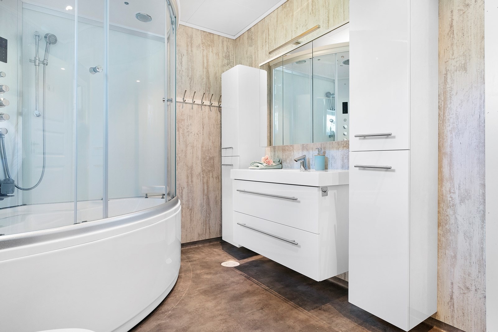 Hvit baderomsinnredning med både skuffer og skap i seksjon, samt speilskap over vask Galleribilde