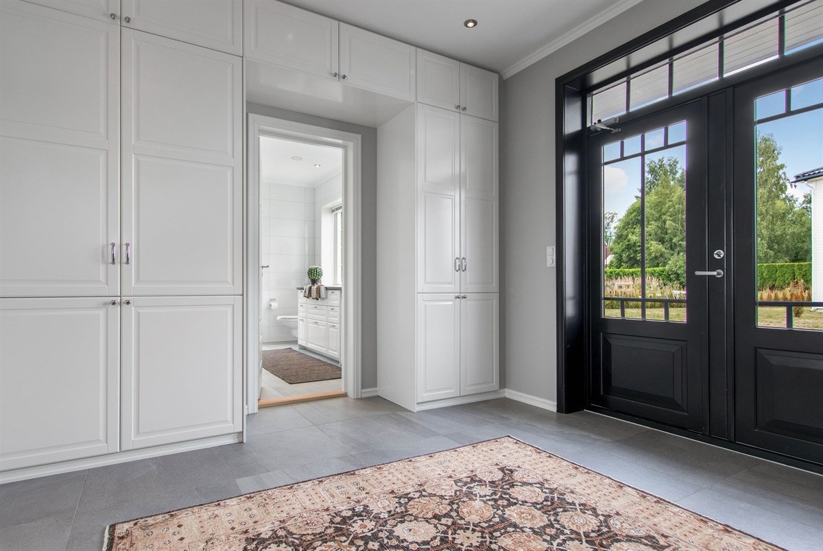 Rommet har grå, store fliser med struktur og gulvvarme, lysegrå vegger og downlights Galleribilde