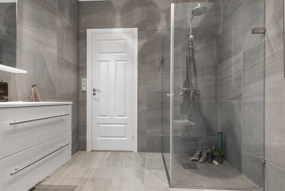 Badet i 1. etg. har store, grå fliser med struktur, downlights og gulvvarme. Galleribilde