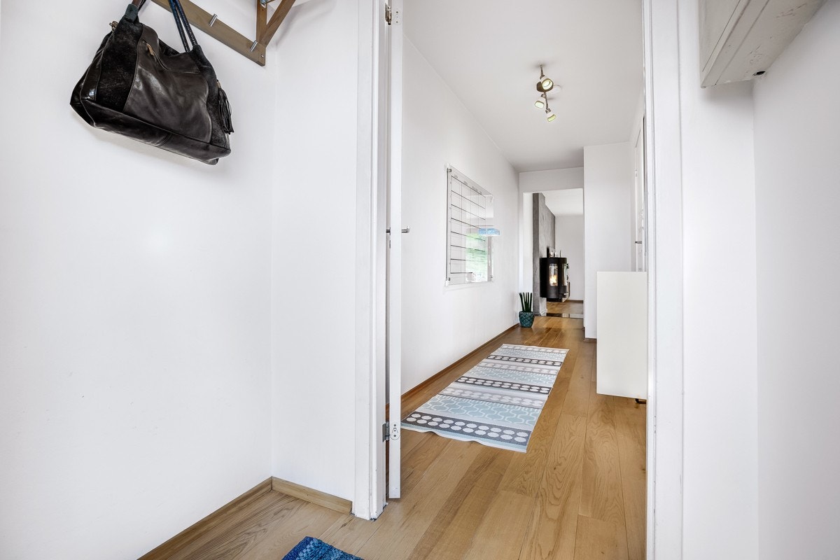 Entré og gang med 1-stavs parkett på gulv og lysmalte veggoverflater. Galleribilde