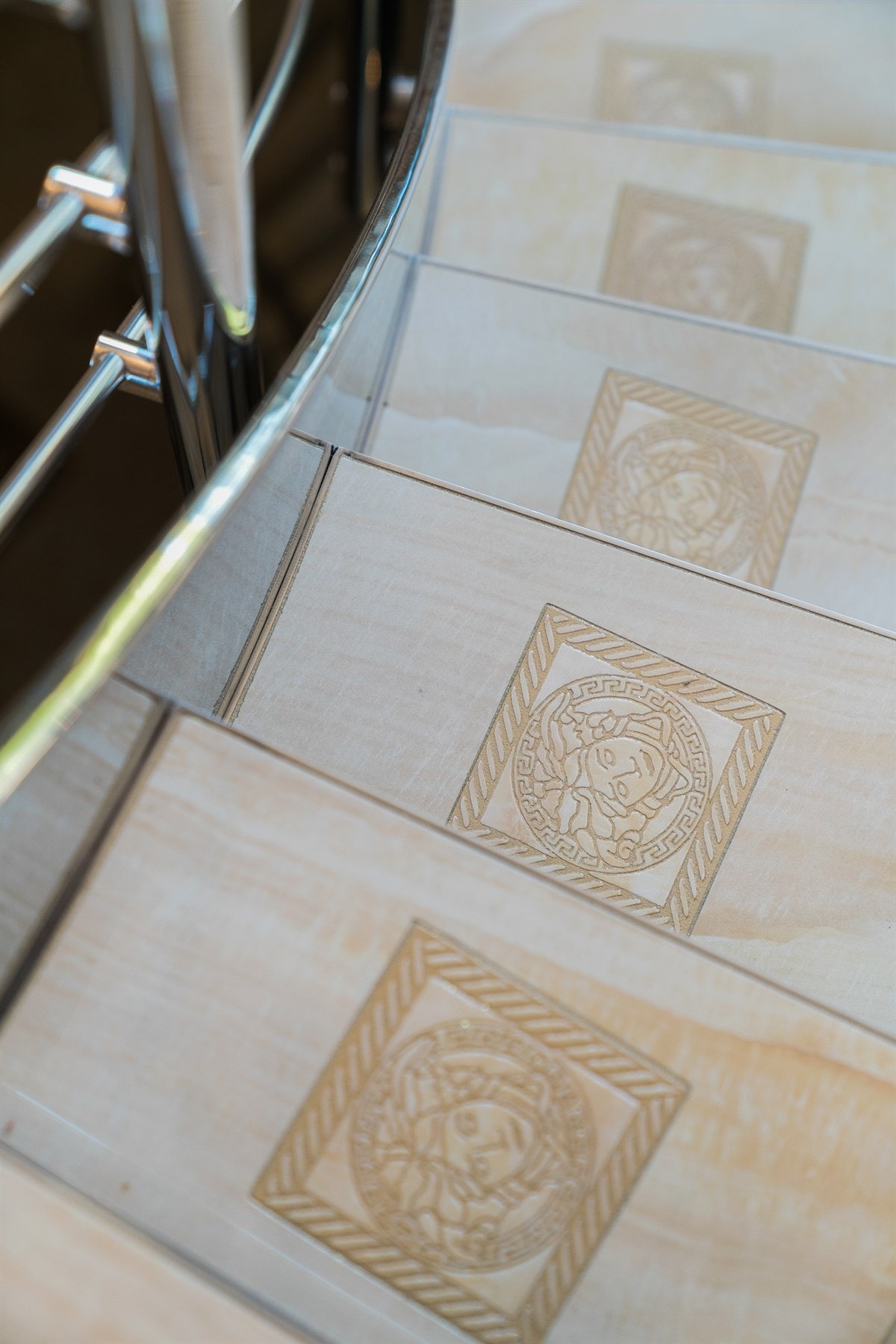 PROAKTIV Eiendomsmegling - Trappeløpet er et smykke i boligen og har en glansfull spesialdesignet stålkonstruksjon med flislagte trinn med Versace-logoen. Galleribilde