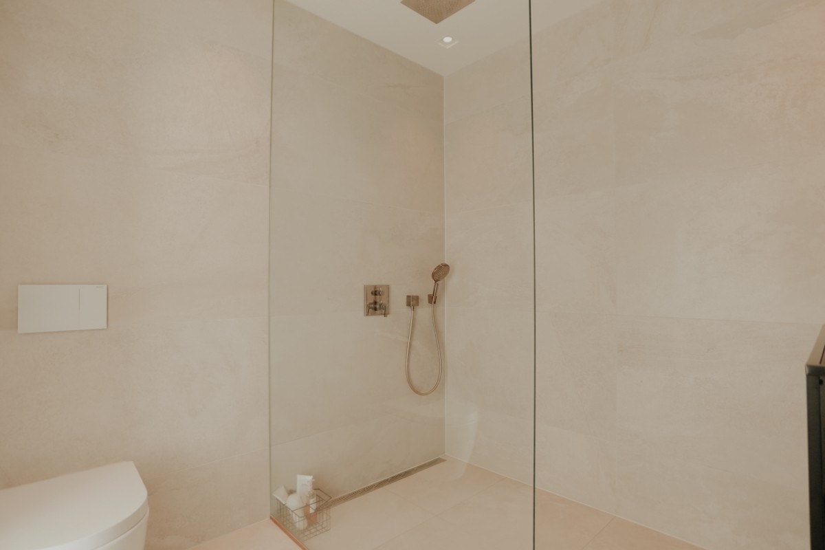 Innredet med en flott dusjnisje med skjermvegg i glass, waterfall dusjhode, praktisk veggsluk, vegghengt klosett, møblement med servant, speil med lyslist. Galleribilde