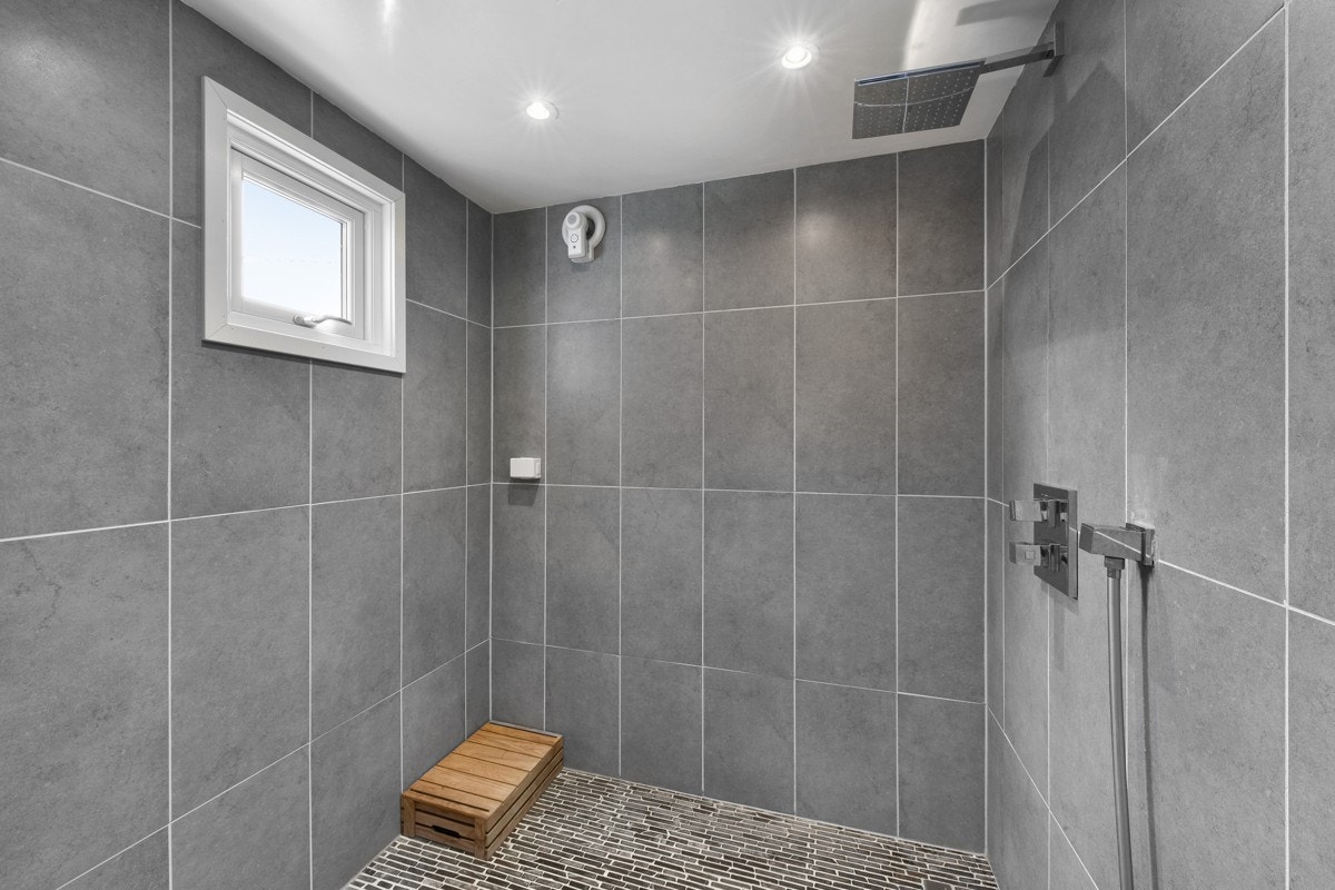 Stor dusjnisje med regnfallsdusj og moasikkfliser på gulvet. Galleribilde