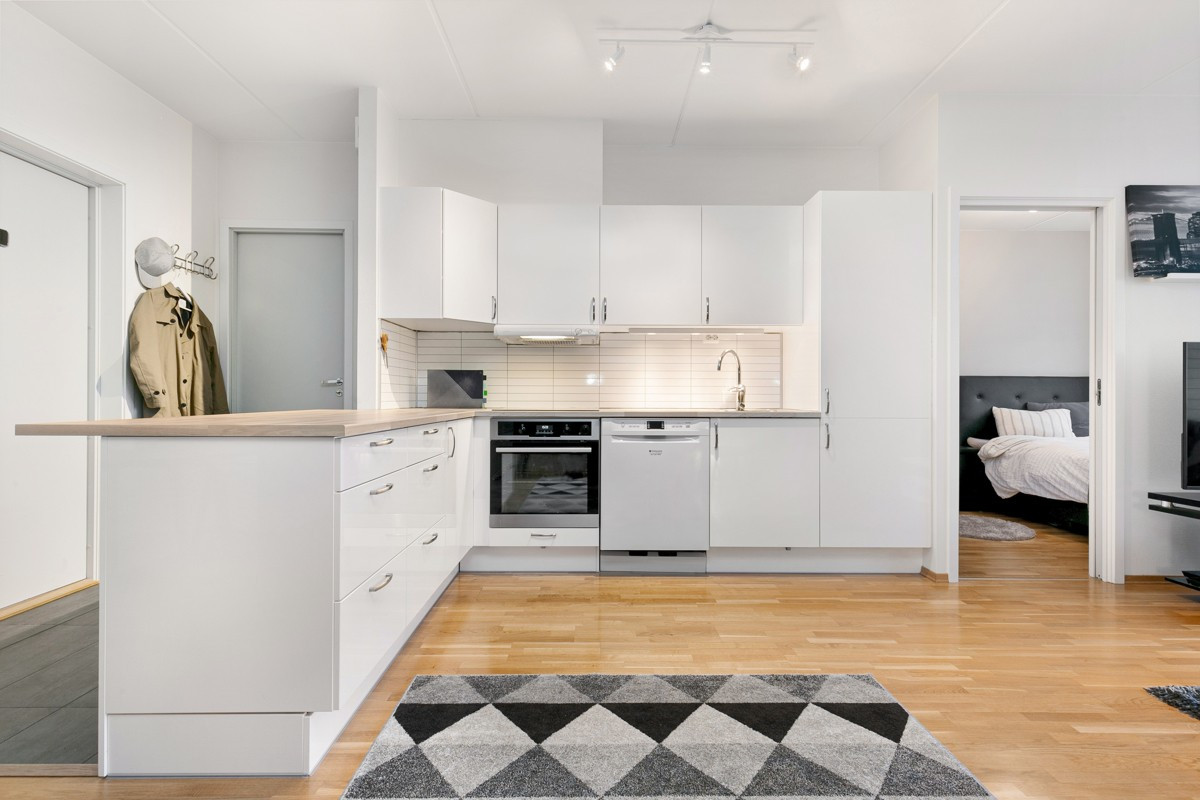Kjøkken er innredet med tidløse glatte hvite fronter og kitchenboard over benk