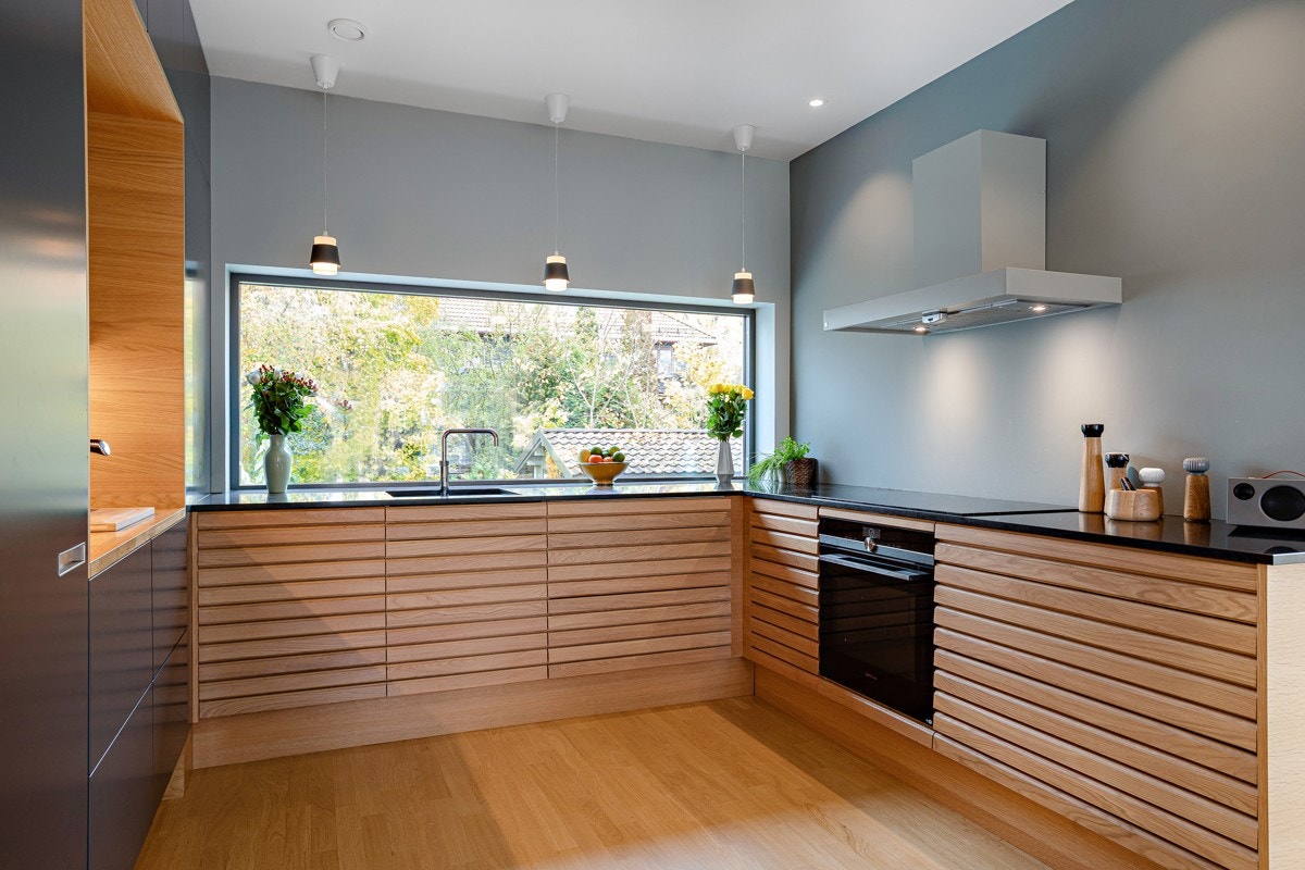 Kjøkkenet er et stilfullt Svanekjøkken med forskjellige fronter og lekker kombinasjon av slette fronter og fronter med liggende spiler i heltre. Galleribilde