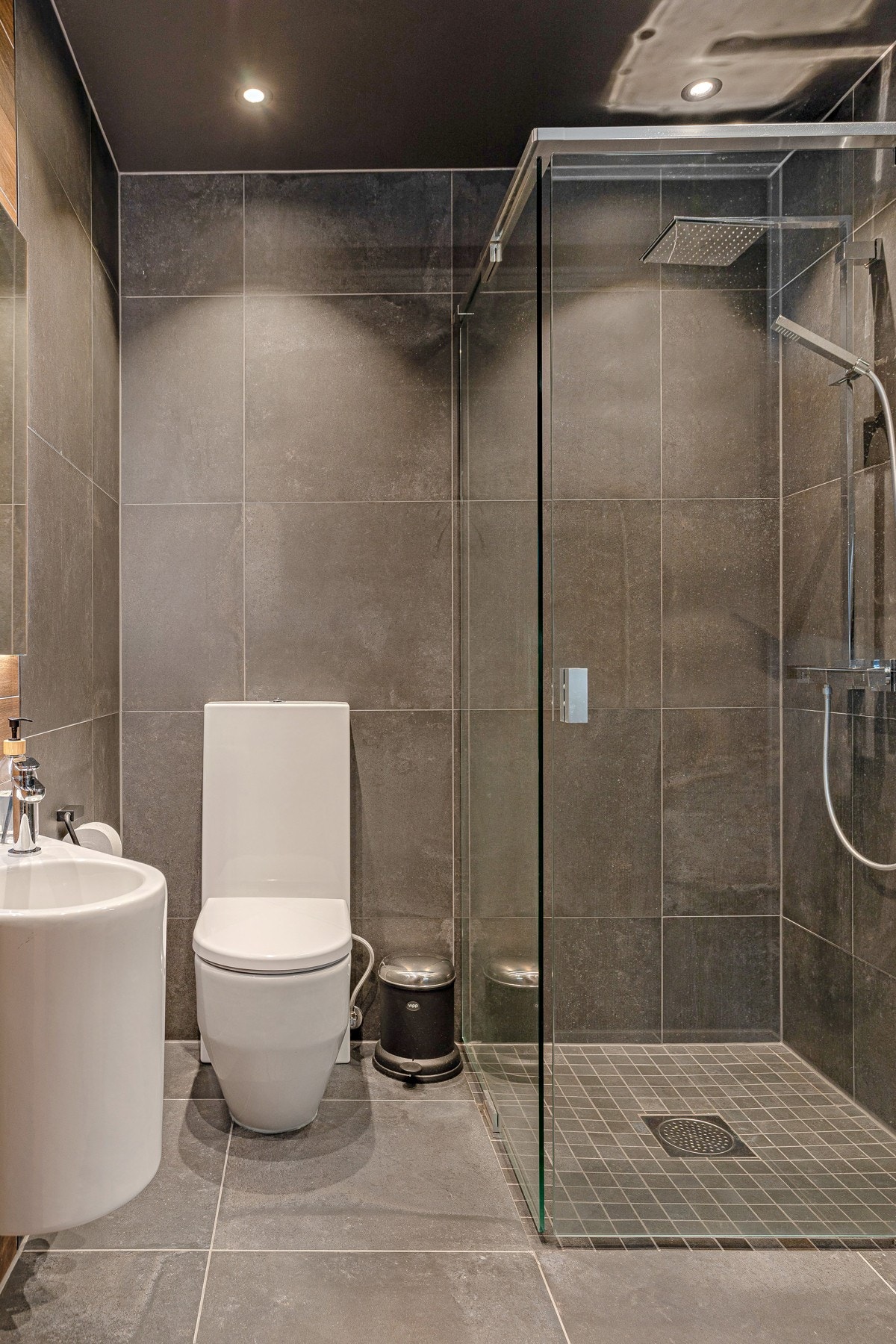 Stilig bad med dusj med glassvegger, servant, speil med lys og toalett. Galleribilde