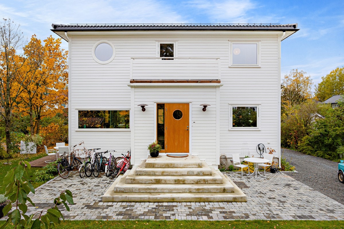 Brosteinbelagt platting foran hovedinngangen. Gjerde og hekk som skjermer mot naboer. Galleribilde