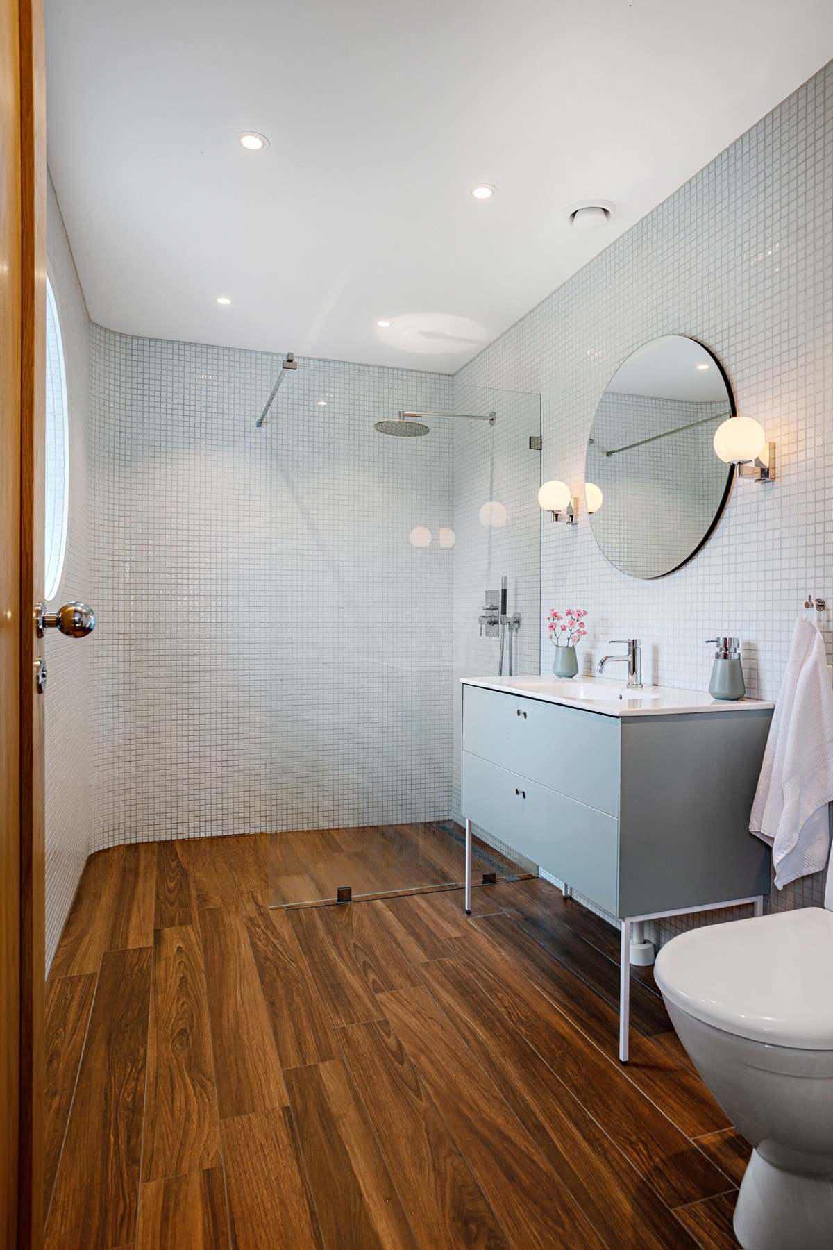 Badet har stilige og gjennomførte detaljer og er installert med dusj med glassvegger, innredning med heldekkende servant og toalett. Galleribilde