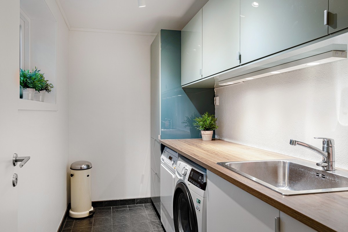 Et svært praktisk vaskerom i kjelleren med innredning, utslagskum og opplegg for vaskemaskin og tørketrommel. Galleribilde