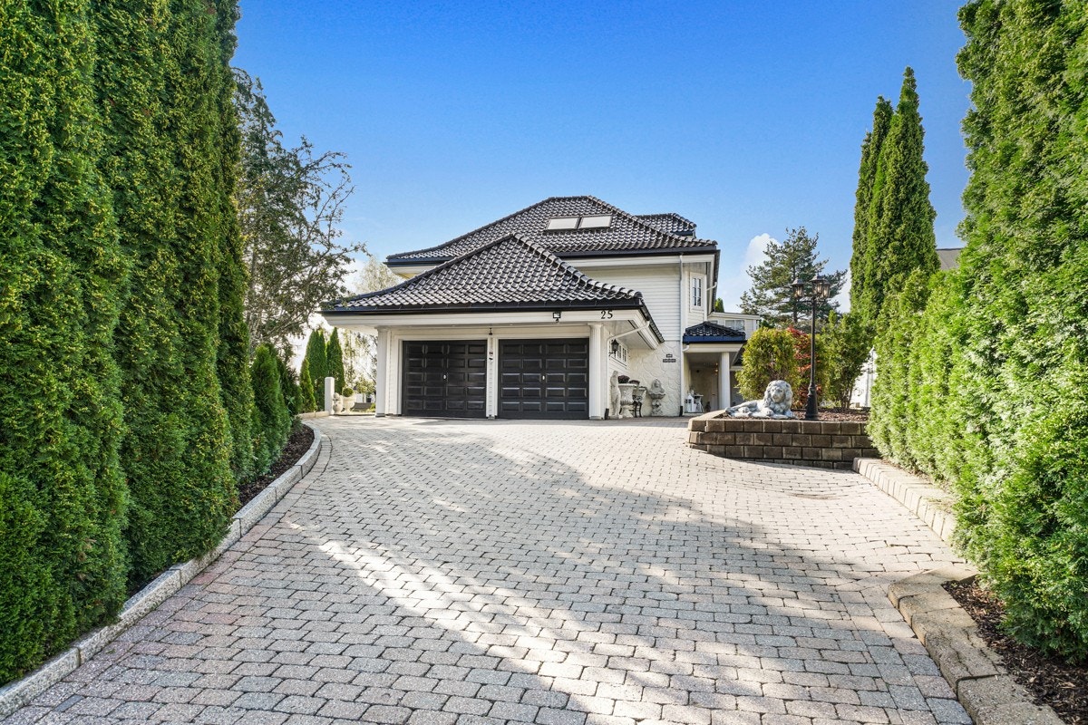Romslig oppkjørsel med belegningsstein og prydbusker. Det er også flere parkeringsplasser på den nedre delen av tomten. Galleribilde