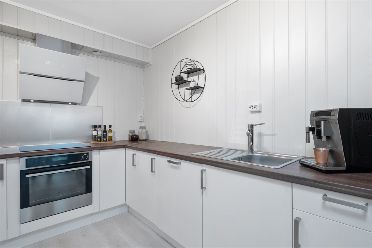 Innredningen består av hvite glatte fronter, laminat benkeplate og stålkum med ett-greps blandebatteri. Galleribilde