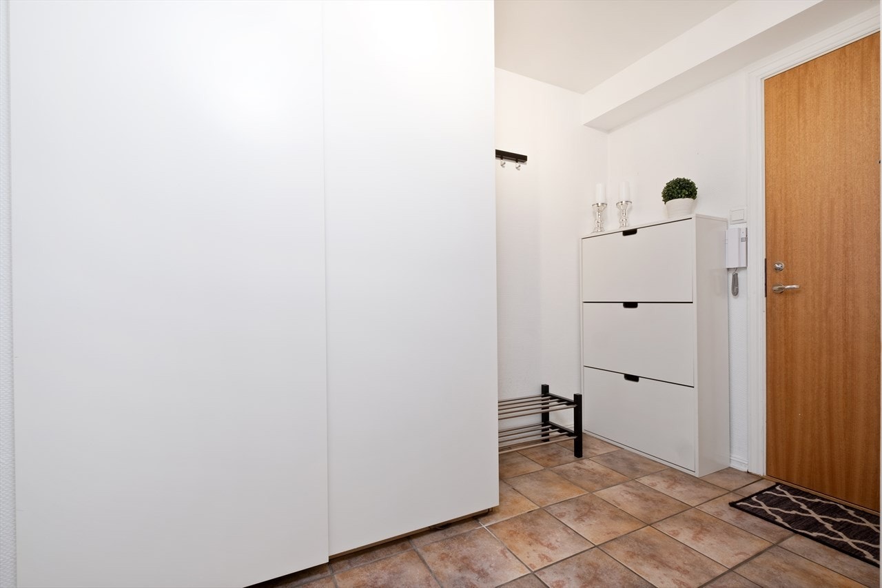 Entréen har flislagt gulv, lysmalte vegger og en skyvedørsgarderobe. Galleribilde