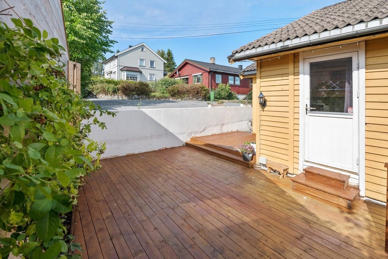 Utvendig hage med gressplen, sydvendt terrasse og flislagt inngangsparti. Galleribilde