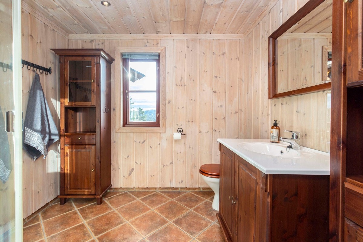 Badet har fliser på gulvet, downlights, gulvvarme, frittstående toalett og dusjkabinett Galleribilde