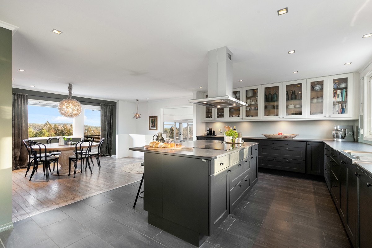 En del av kjøkkenet har benkeskap og overskap med glassfronter og benkebelysning. Galleribilde