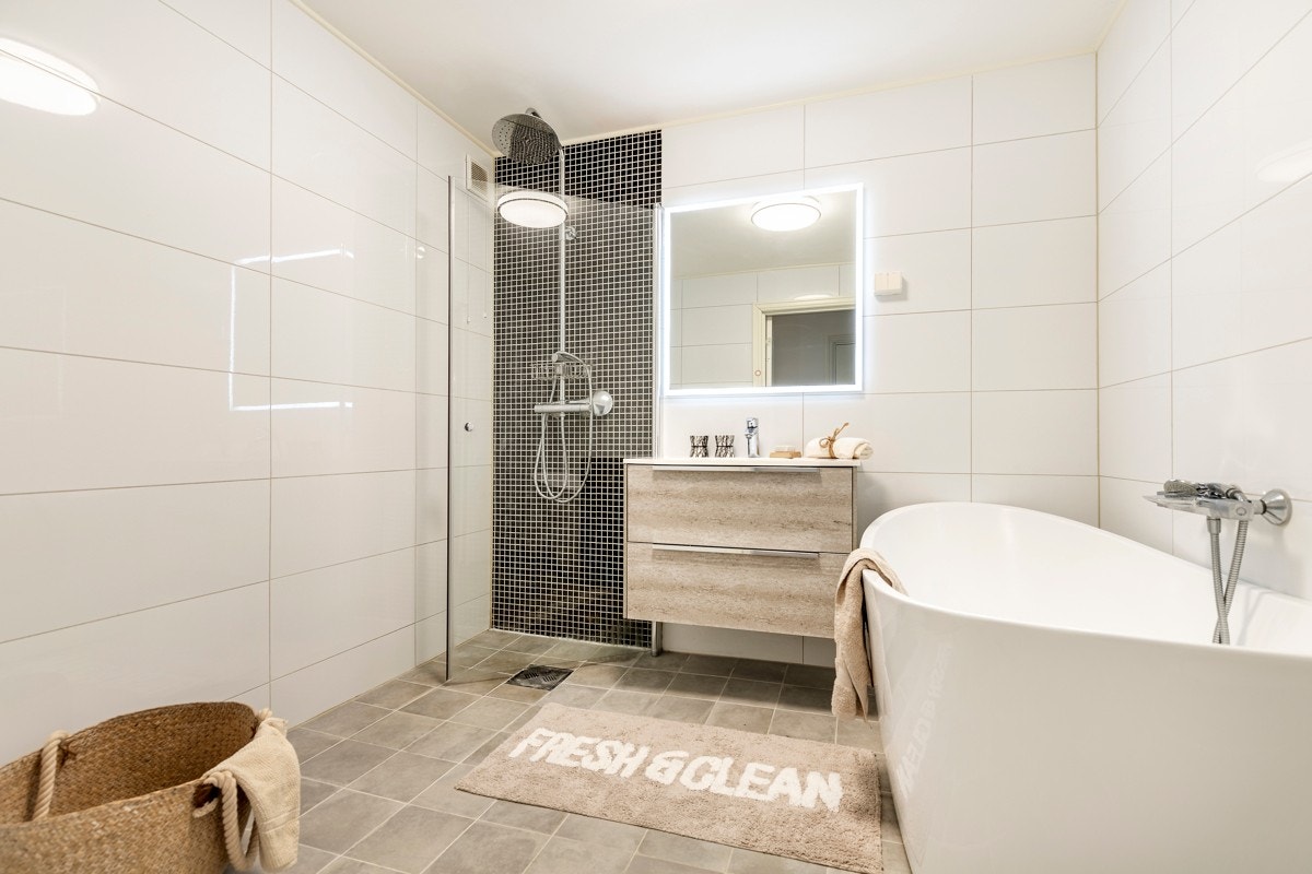 Badet har heldekkende servant, servantmøblement, speil med lyslist rundt, veggmontert toalett, regnfallsdusj, mekanisk avtrekk og opplegg for vaskemaskin. Galleribilde