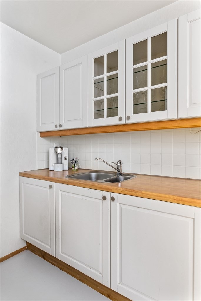 Det er lagt fliser mellom benkeplaten i laminat og overskapene. Galleribilde