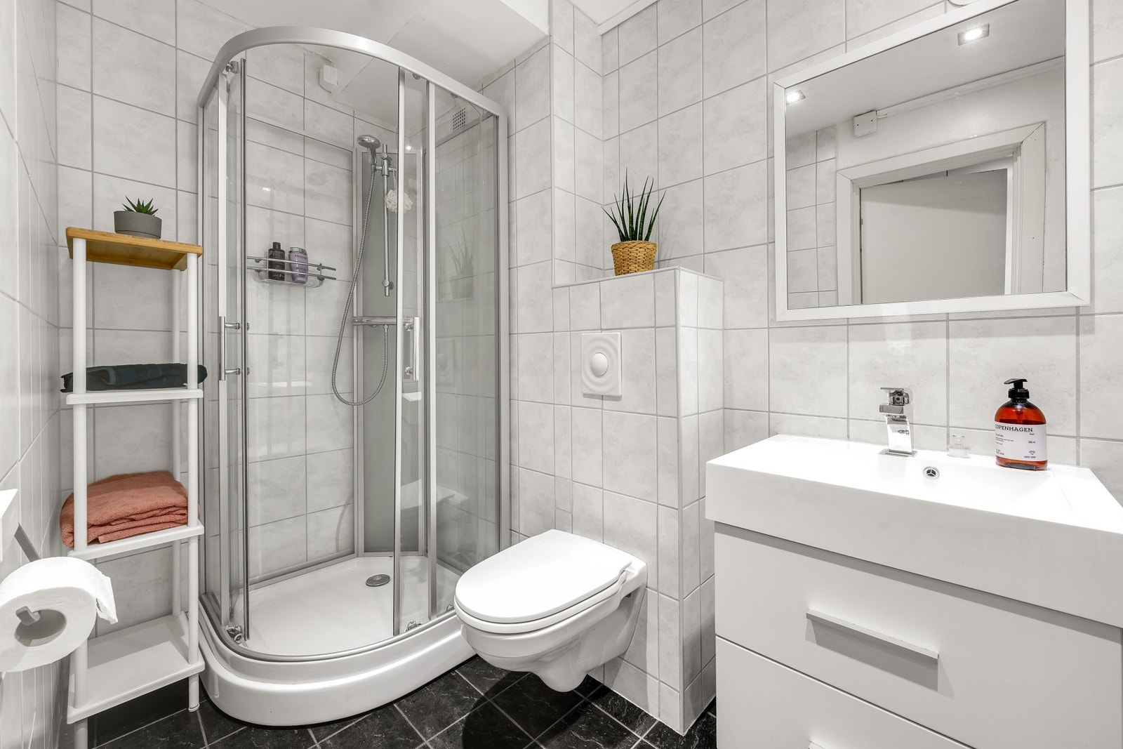 Pent flislagt baderom fra 2007 med servant på underskap, speil, hyller og downlights i himling. Galleribilde