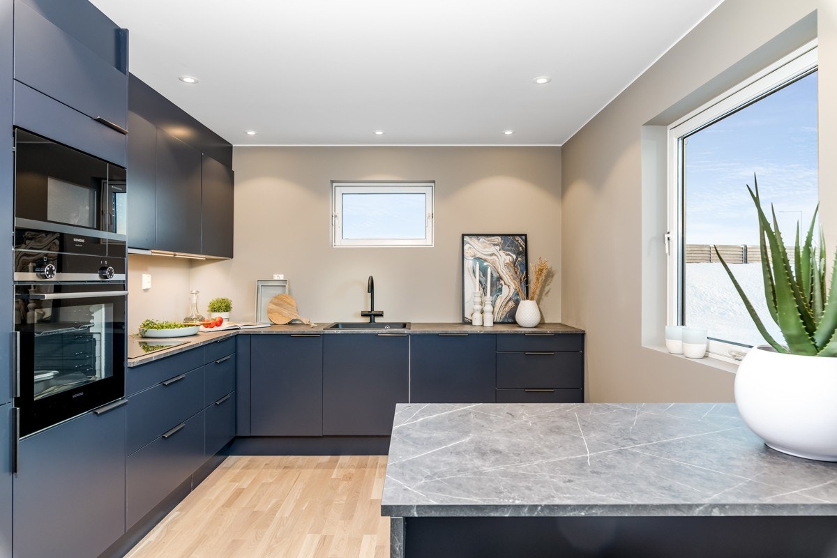 Innredningen har glatte fronter i dyp blåtone og er utformet i vinkel, supplert av en barløsning med sitteplasser. Galleribilde