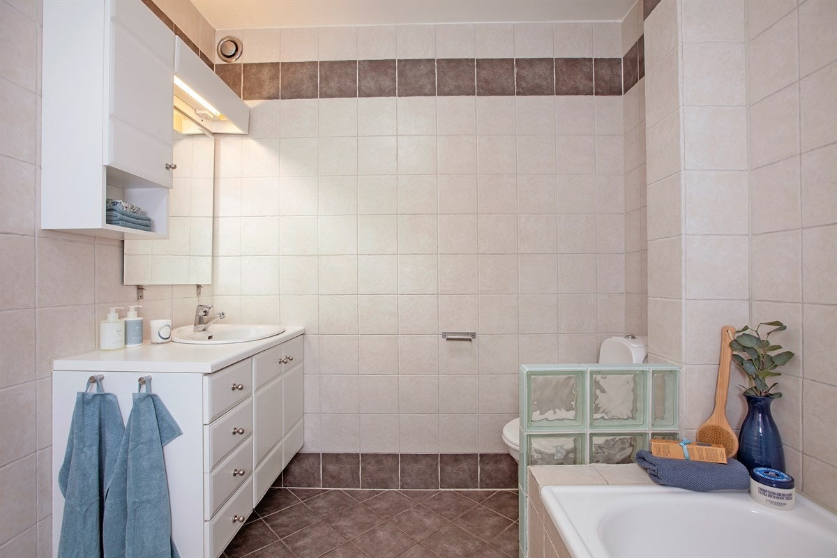 Badet har bl.a. innmurt flislagt badekar med dusj og forheng Galleribilde