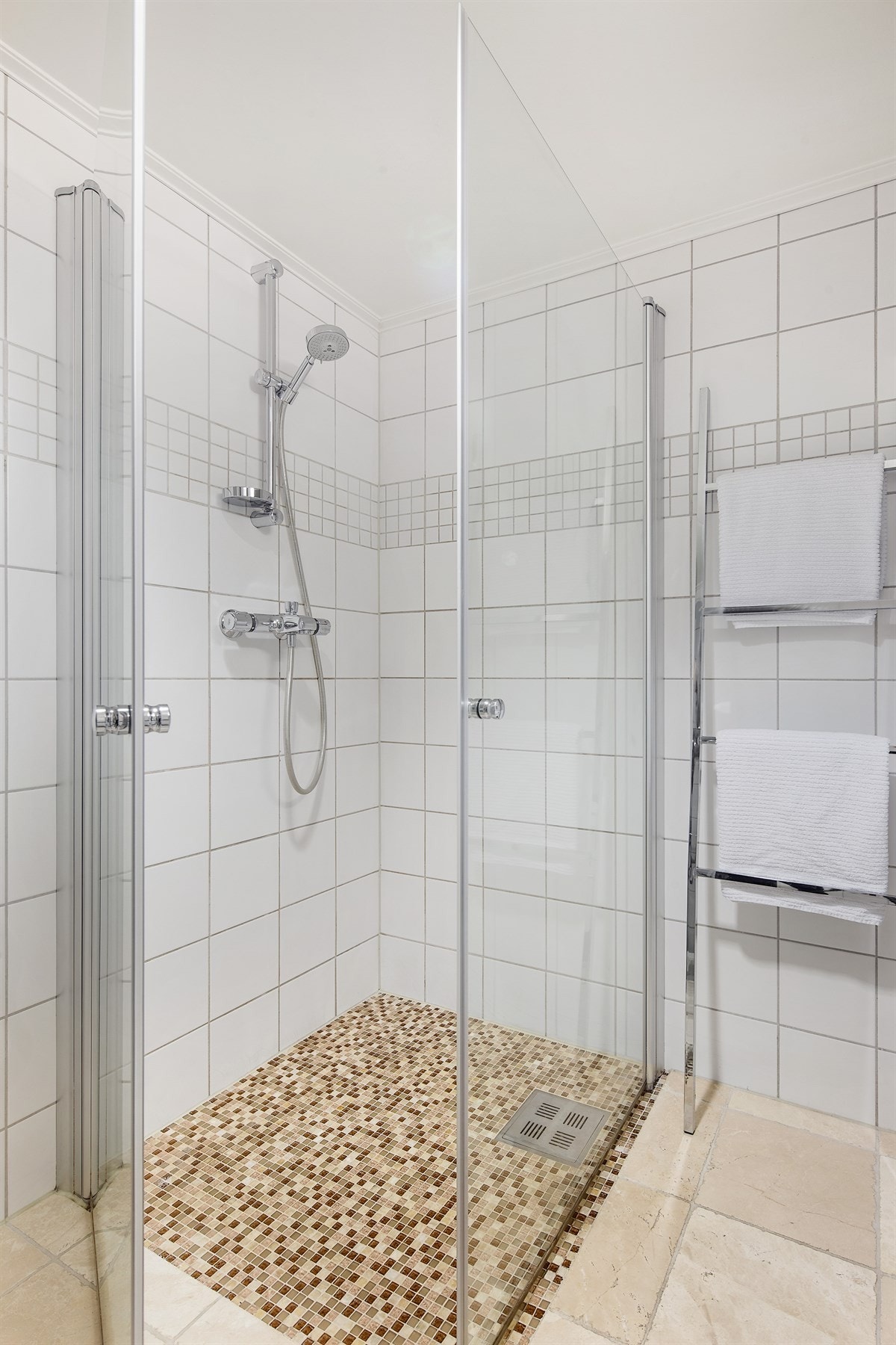 Dusjhjørne med mosaikkfliser og innfellbare glassdører. Galleribilde