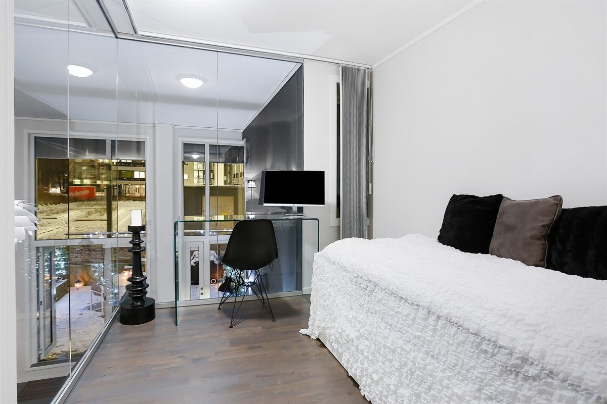 På mesaninen ligger også et lyst, luftig innredet rom med vindu som kan benyttes som gjesterom/kontor. Rommet har glassvegger mot stuen i etasjen under, og er utstyrt med lammeller som skjermer rommet når det benyttes som soverom. Galleribilde