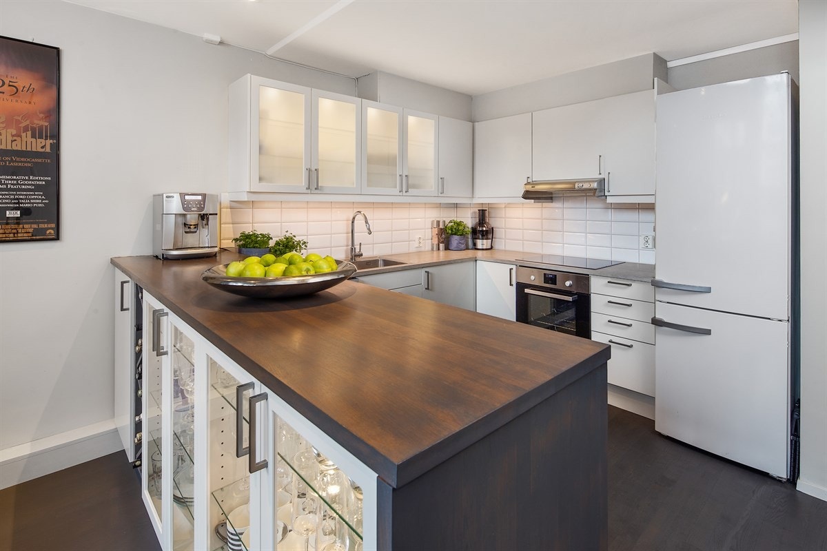 Kjøkkenet ble oppgradert i 2015 og ligger i åpen løsning med den luftige stuen. Innredningen er fra Sigdal, med god skapplass, slette, hvite fronter og vitrineskap med frostet glass. Galleribilde