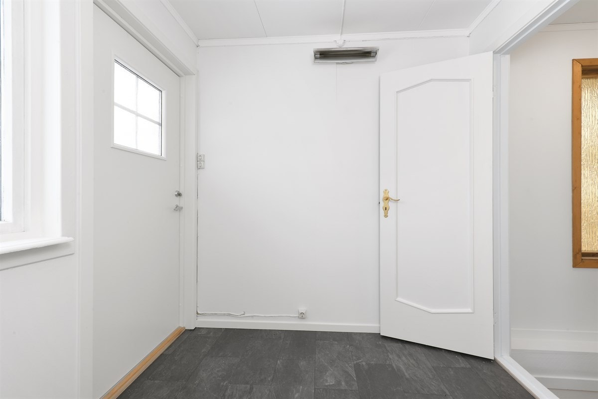 Romslig entré med moderne laminatgulv og lysmalte panelplater. Galleribilde