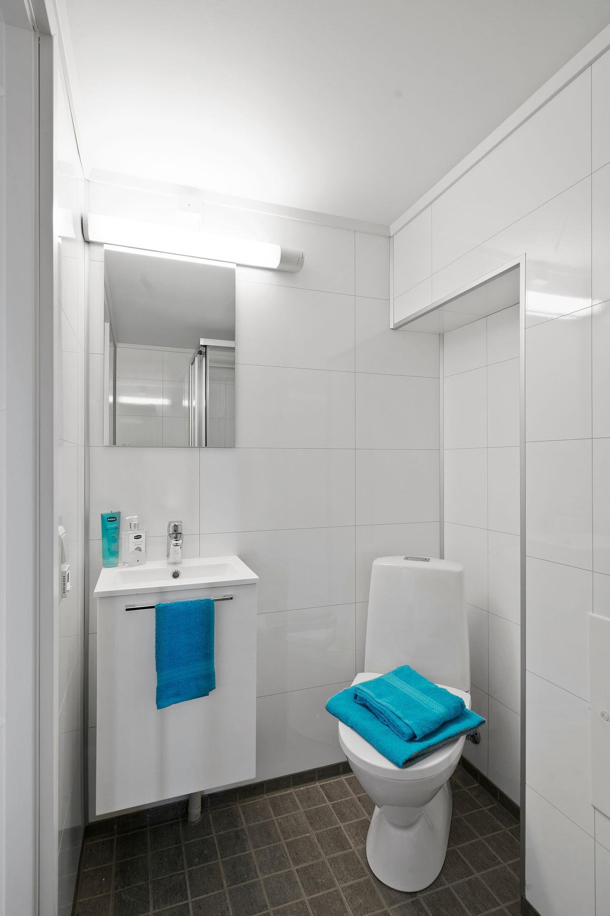 Badet er stilrent med fliser på gulv og baderomsplater på vegger Galleribilde