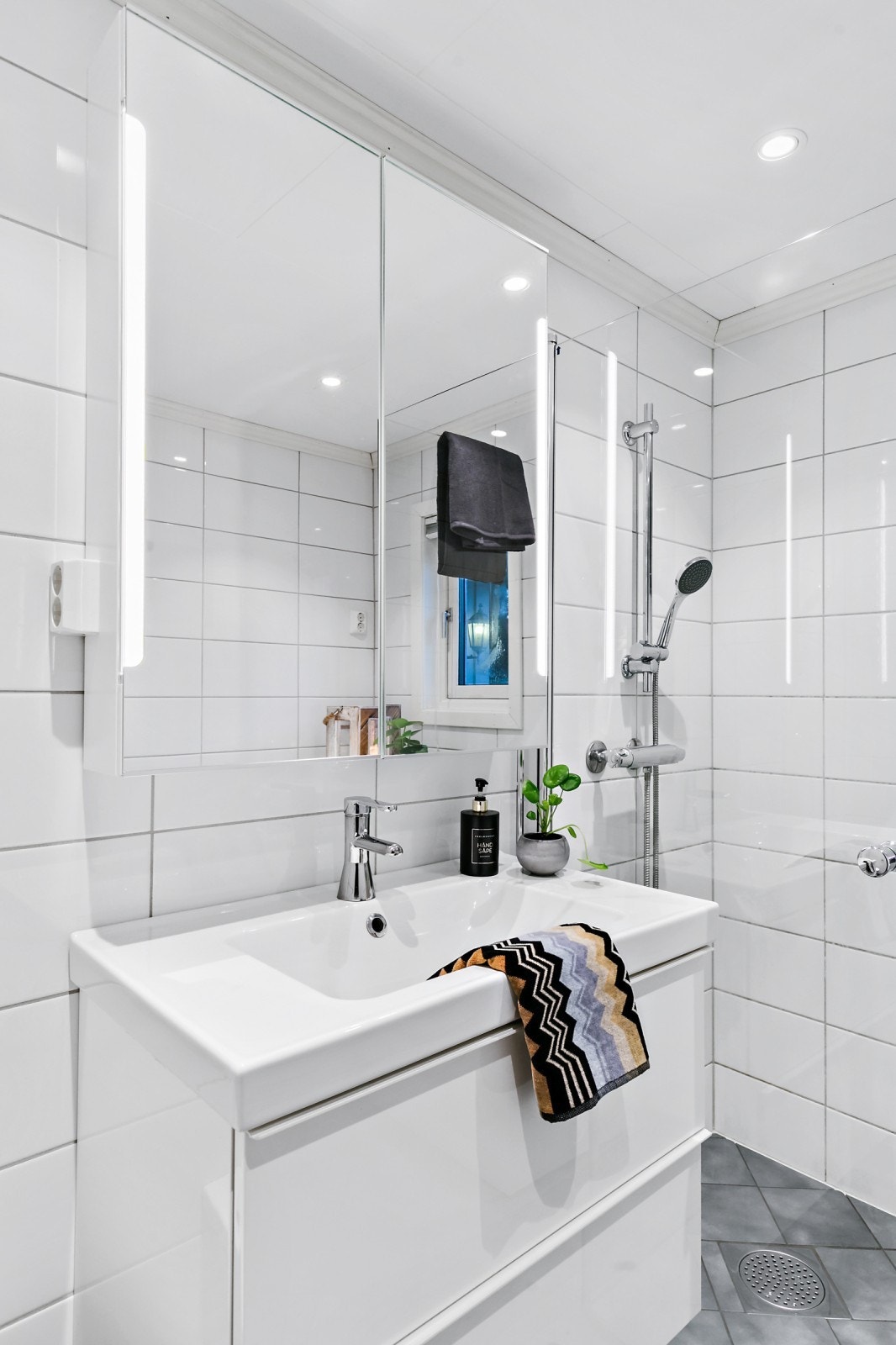 Badet er utstyrt med dusjvegger, servant og toalett. Galleribilde