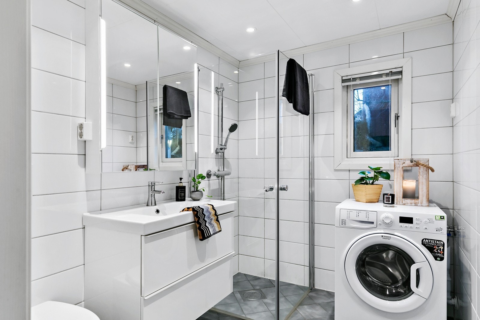 Pent og lyst flislagt bad med varmekabler i gulv og downlights i himling. Innfellbare dusjvegger for å optimalisere arealbruken. Galleribilde