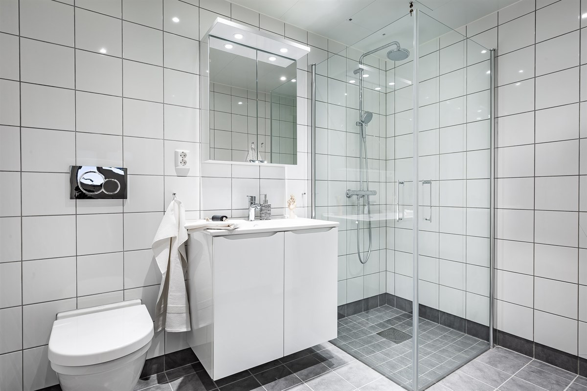 Badet er flislagt, med dusjhjørne, downlights og varme i gulv