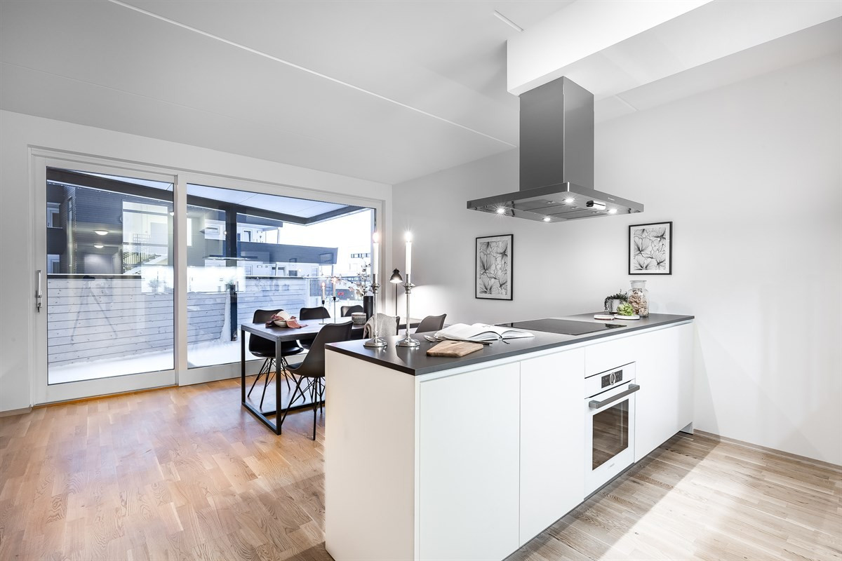Moderne kjøkken med stor kjøkkenøy og integrerte hvitevarer