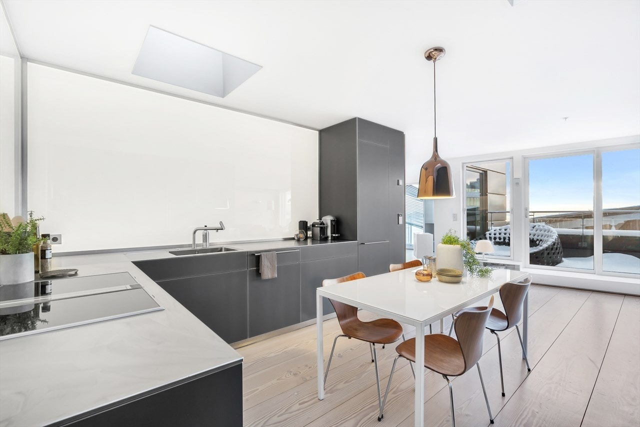 Lekker stål benkeplate. Avfallskvern i kjøkkenbenken. Vegg over kjøkkenbenken er kledd med glassplate og bakenforliggende belysning. Galleribilde