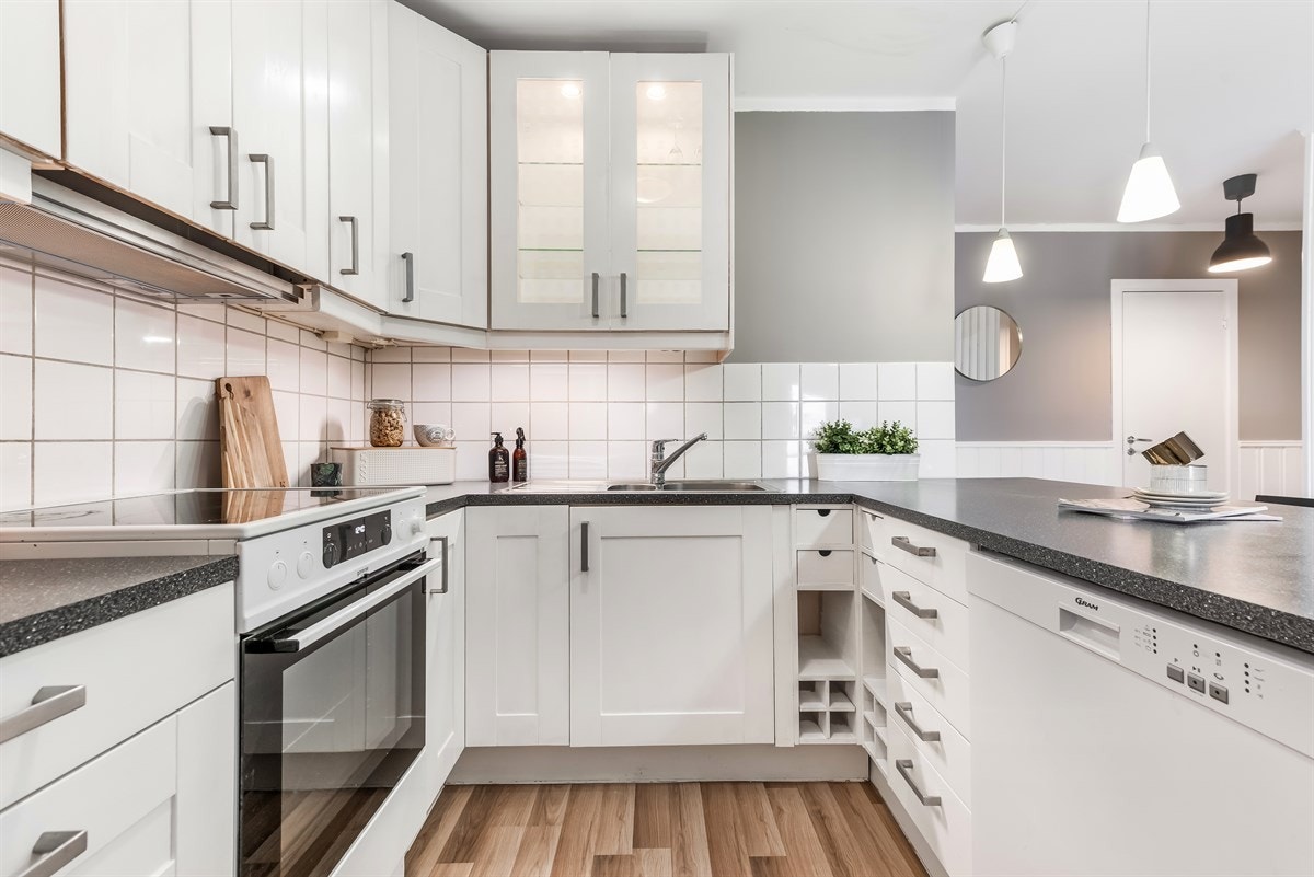 Kjøkken fremstår med profilerte fronter, 4 vitrinefronter, laminat benkeplate m/fliser over benk og oppvaskkum. Galleribilde