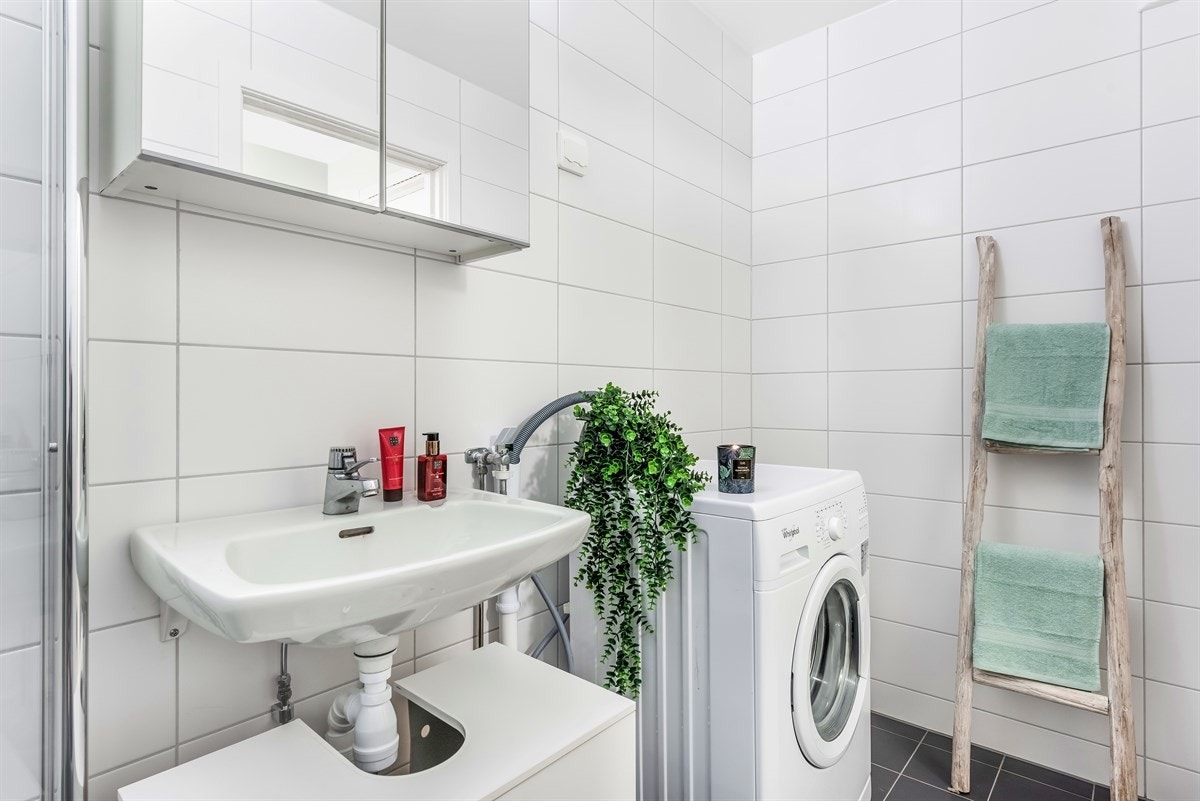 Badet fremstår med porselensservant, veggmonterte svingbare dusjvegger av herdet glass og termostat dusjbatteri. Opplegg vaskemaskin. Galleribilde