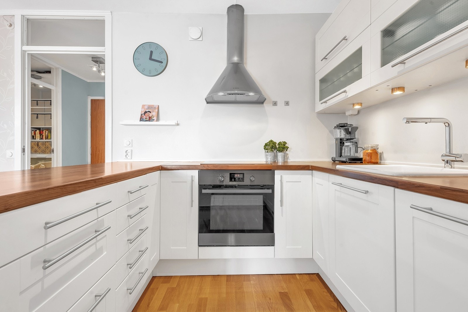 Kjøkken - Pen kjøkkeninnredning med hvite, profilerte fronter og håndtak i stål Galleribilde