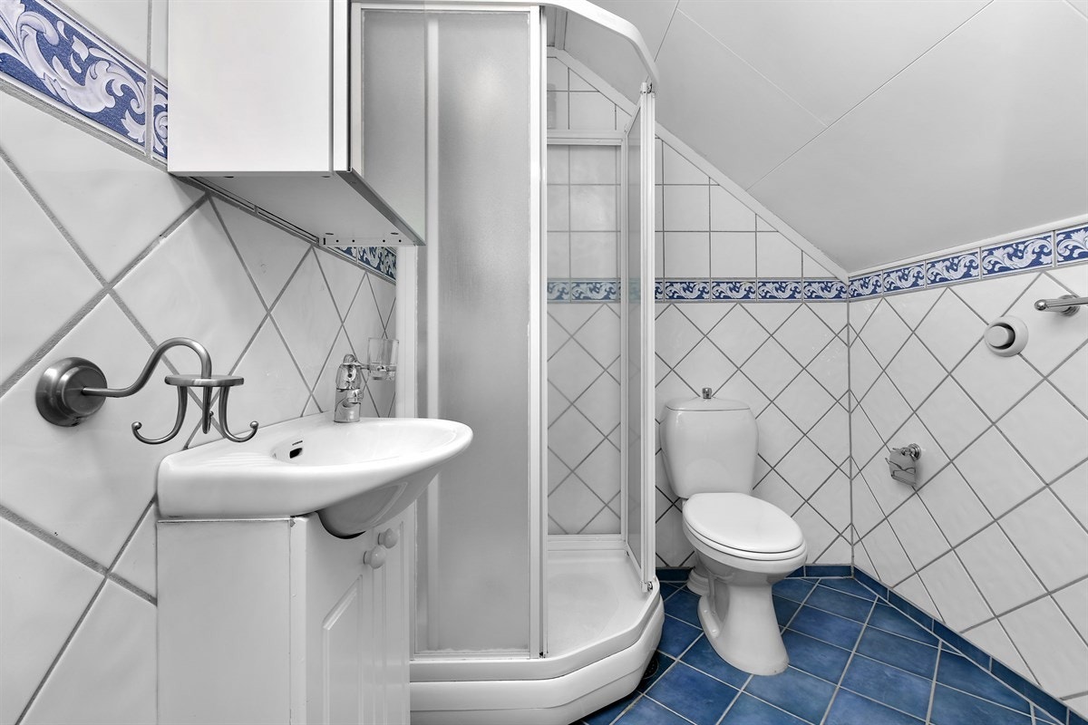 Badet som ligger i andre etasje har flislagte flater, toalett og dusjkabinett. Det er servantinnredning med hvite profilfronter og speilskap. Galleribilde