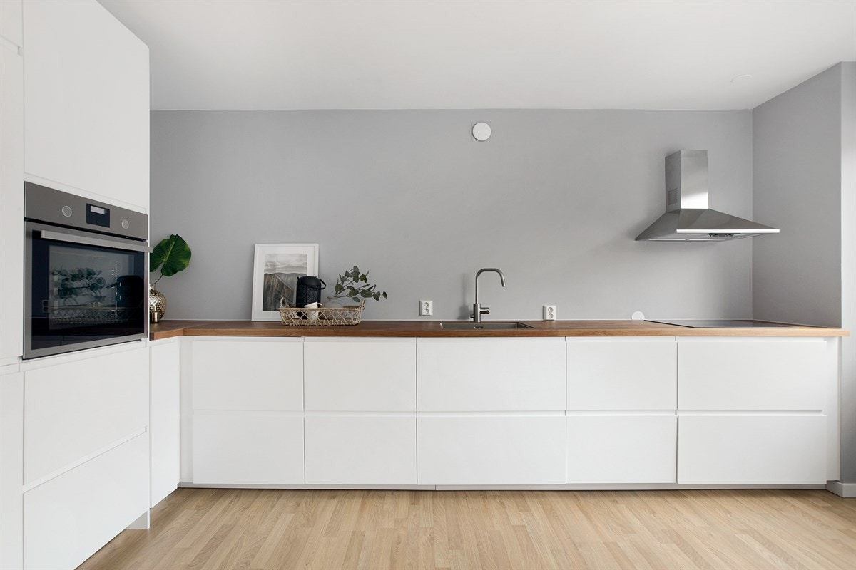 Kjøkkeninnredning fra IKEA (2017) med hvite fronter, enkel underlimt oppvaskkum, ettgrepskran og laminert benkeplate. Galleribilde