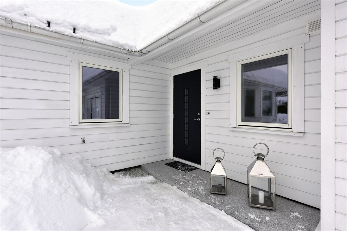 Boligen har et lunt, overbygget inngangsparti med flislagt platting og sortmalt dør med glassfelt. Galleribilde