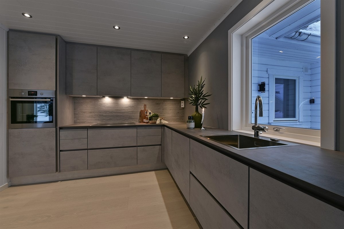 Innredningen fra 2018 har gråfargede, slette fronter med integrerte håndtak, og laminert benkeplate med nedfelt oppvaskkum under vindu. Galleribilde