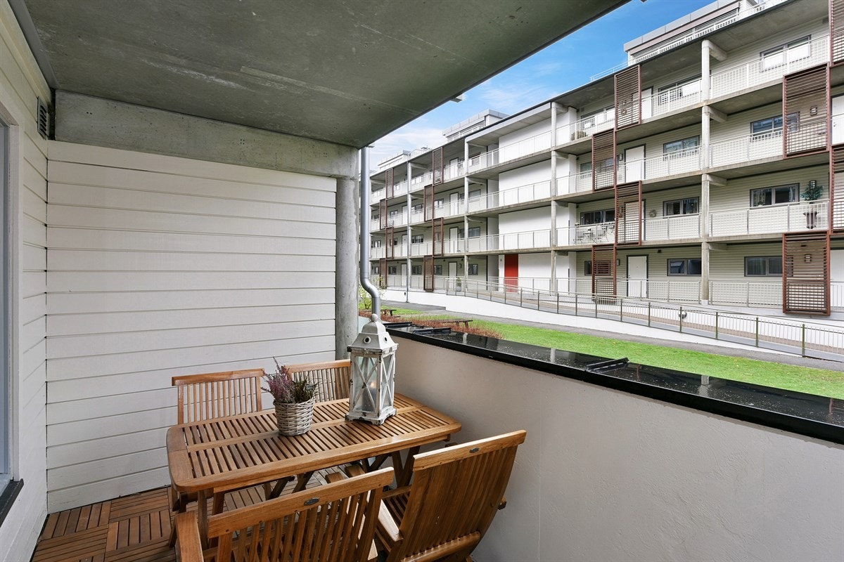 Verandaen har treheller og et betongrekkverk med sort stålbeslag og to felter av frostet glass. Det er god plass for en komfortabel sittegruppe der man nyte lune sommerkvelder. Galleribilde