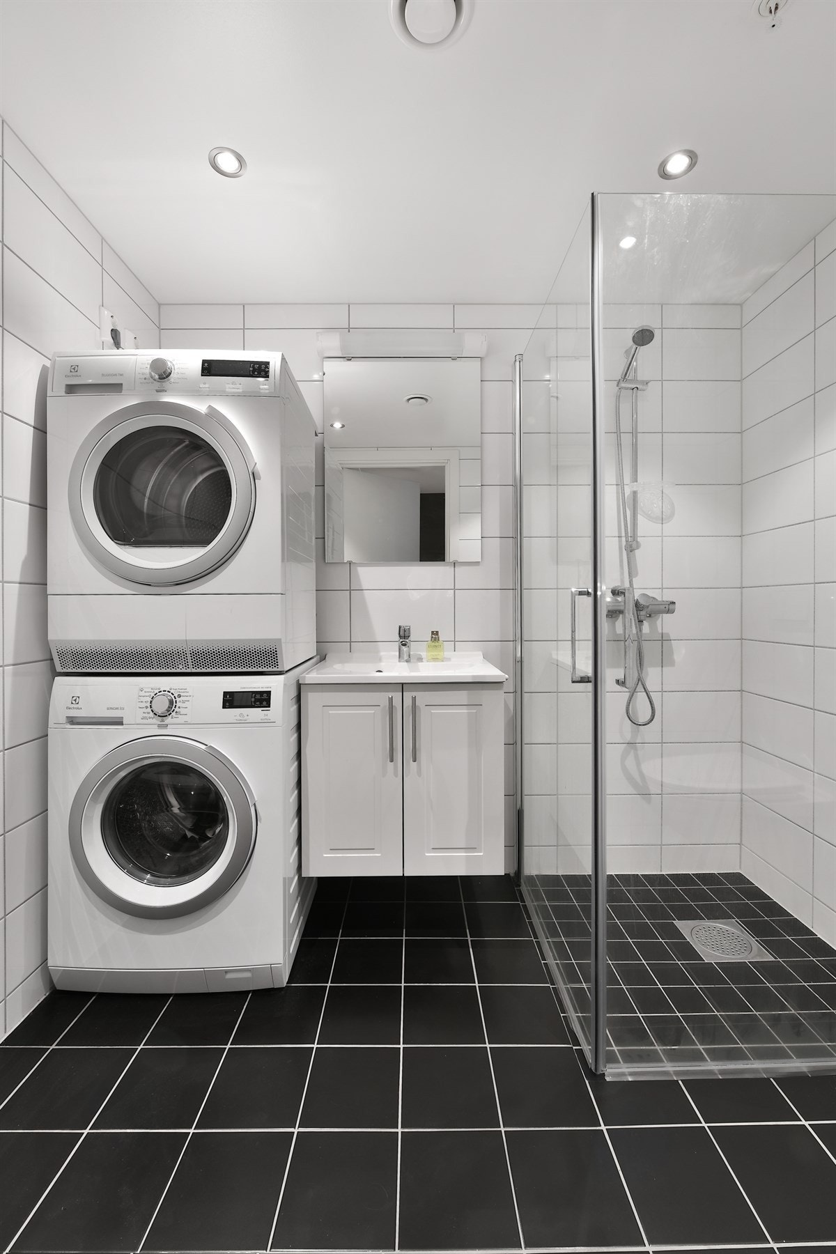 Badet er pent og helfliset, med hvite vegger, mørkt gulv med behagelig varme og downlights i himling. Opplegg for vaskemaskin. Galleribilde